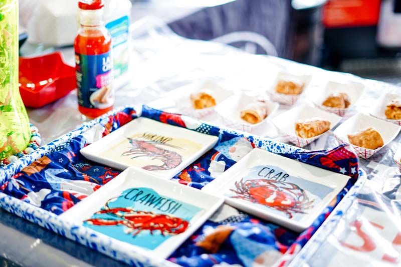 A table topped with plates of food and a bottle of hot sauce.