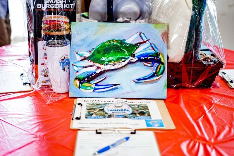 A painting of a blue crab is on a clipboard on a table.