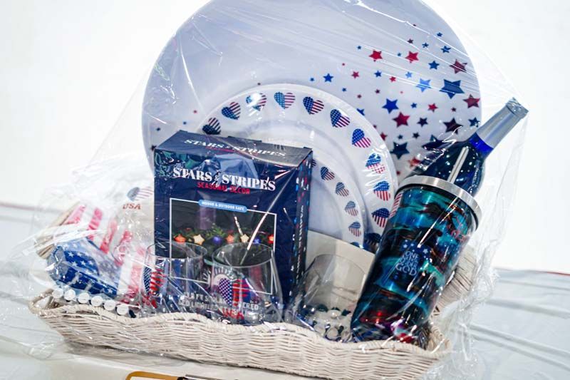 A basket filled with plates , cups , and a bottle.