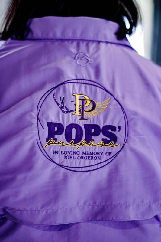 A person wearing a purple jacket with the word pops on it