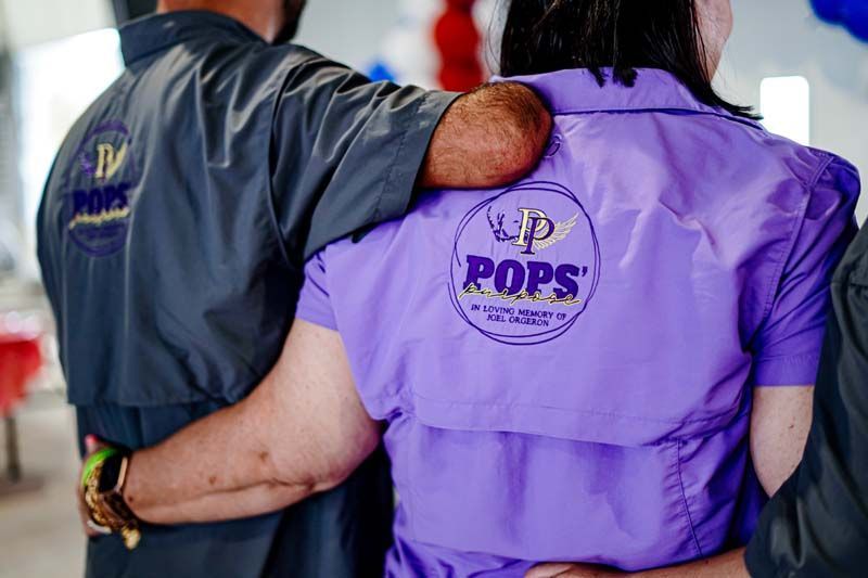 A man is hugging a woman in a purple shirt that says pops.