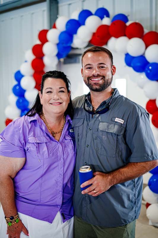 A man and a woman are posing for a picture in front of balloons.