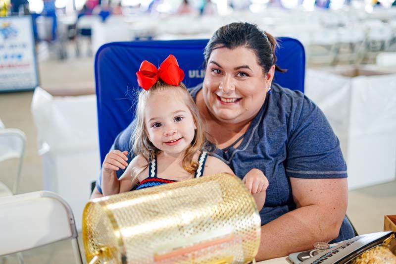 A woman and a little girl are sitting next to each other in a chair.