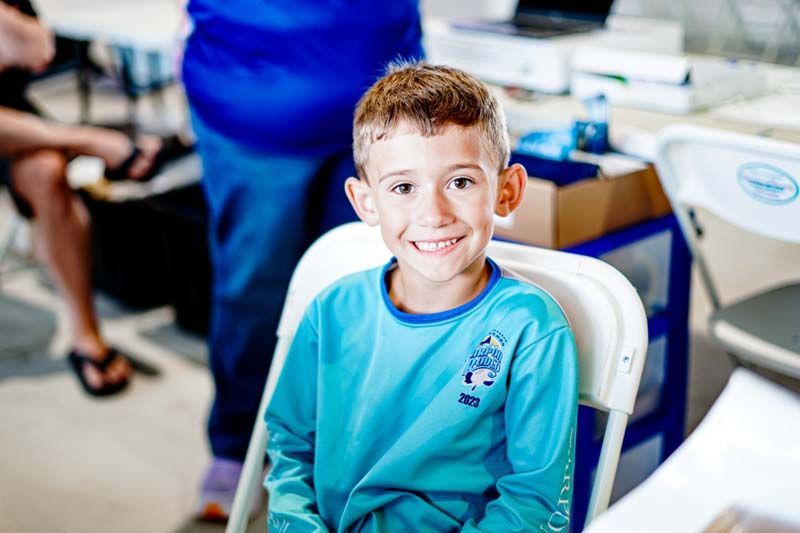 A young boy is sitting in a chair and smiling at the camera.