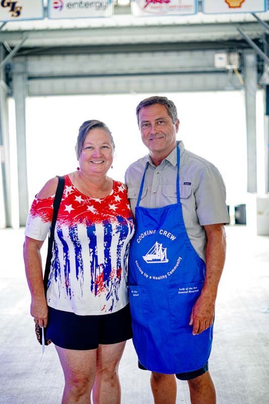 A man and a woman are posing for a picture while wearing aprons.