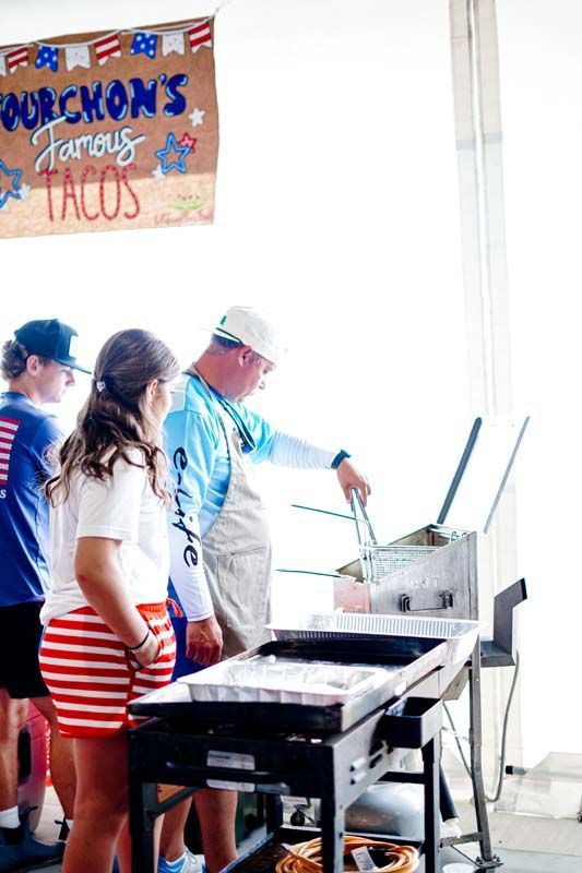 A group of people are standing around a table eating tacos.