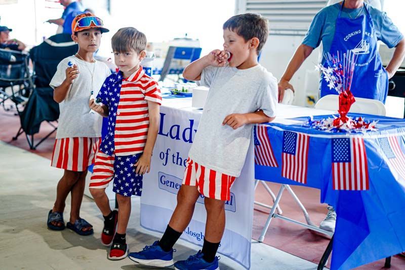 Three young boys are standing in front of a table that says lad