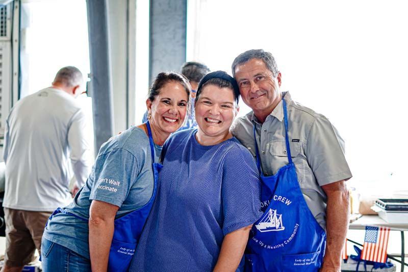 A group of people wearing blue aprons are posing for a picture.