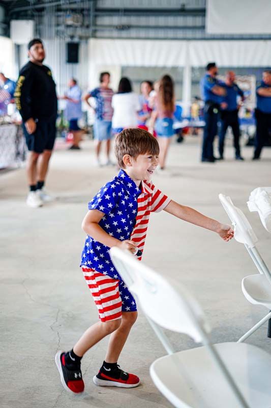 A young boy in an american flag outfit is playing with a frisbee in a room.
