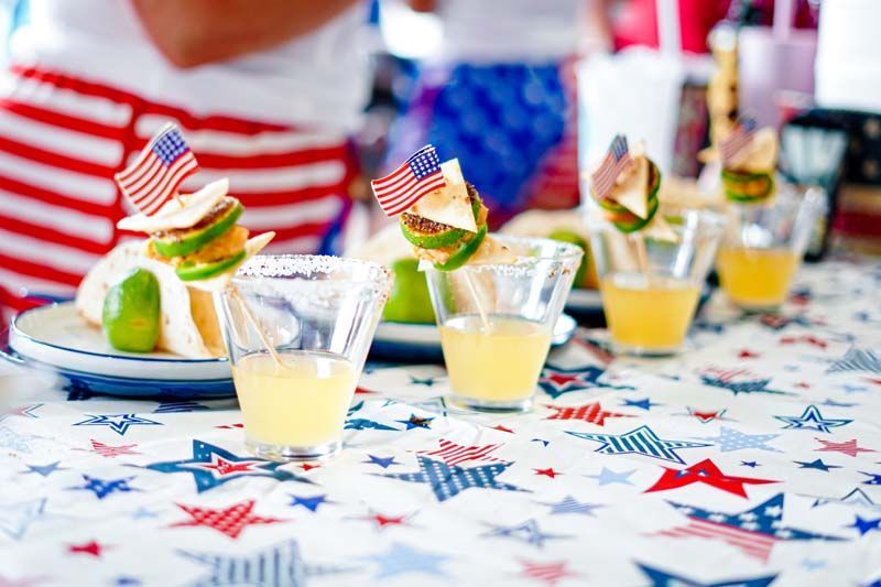 A table topped with glasses of drinks and a plate of food.