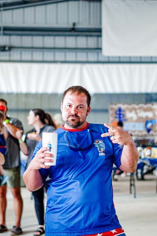 A man in a blue shirt is holding a cup in his hand.