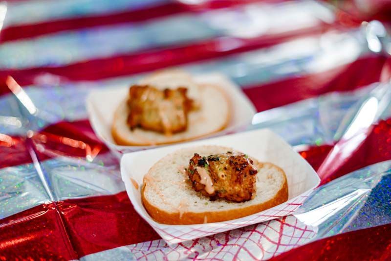 Two sandwiches are sitting on a red white and blue table cloth.