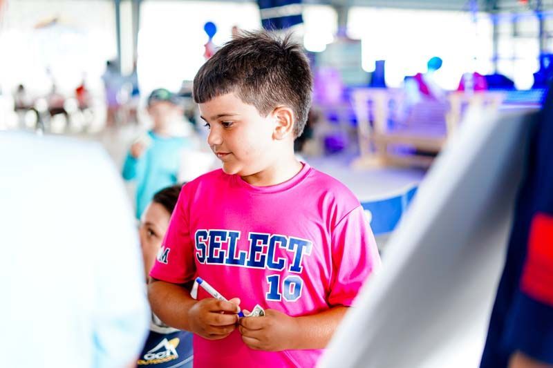 A young boy wearing a pink shirt with the number 10 on it.