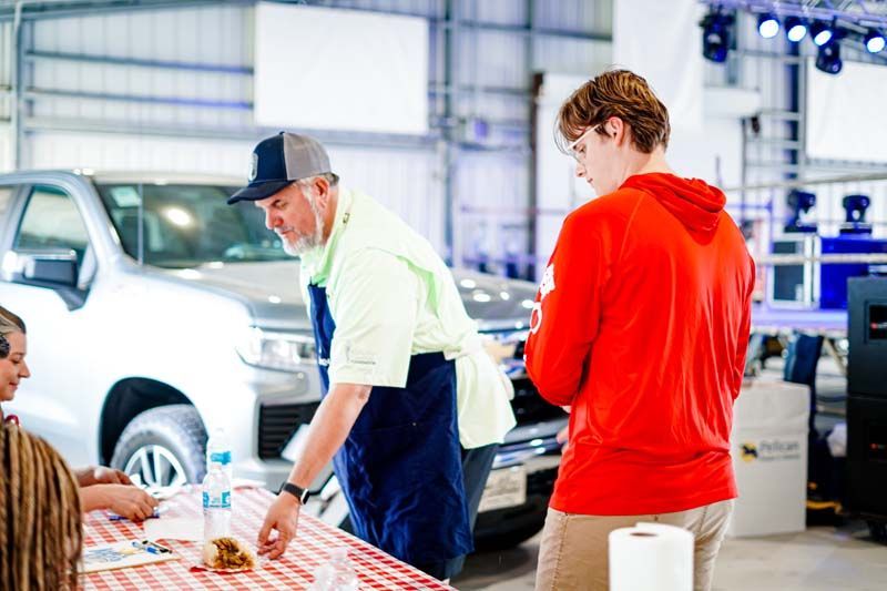 A man in an apron is standing next to a boy in a red hoodie.