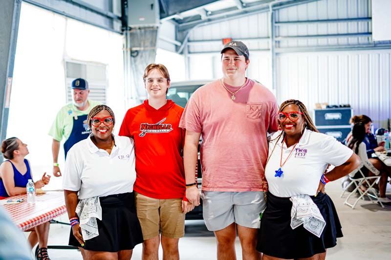 A group of people standing next to each other in front of a car.