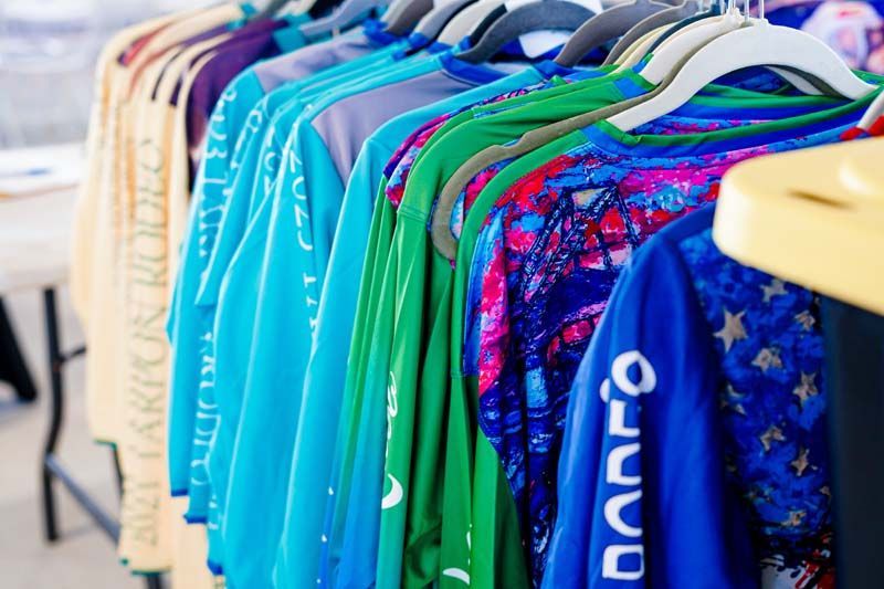 A row of colorful shirts are hanging on a rack.