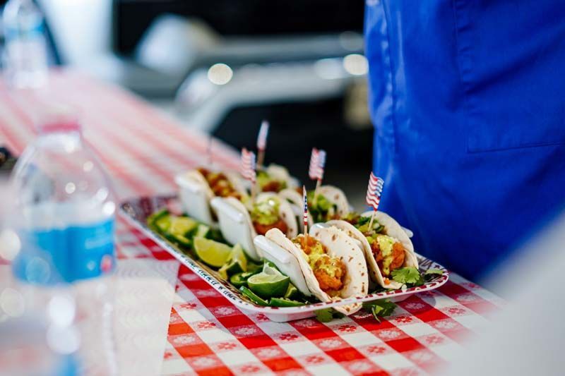 A tray of tacos on a checkered table cloth on a table.