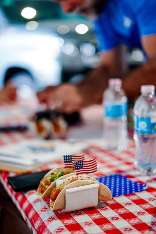 Two tacos with american flags on them are sitting on a checkered table cloth.