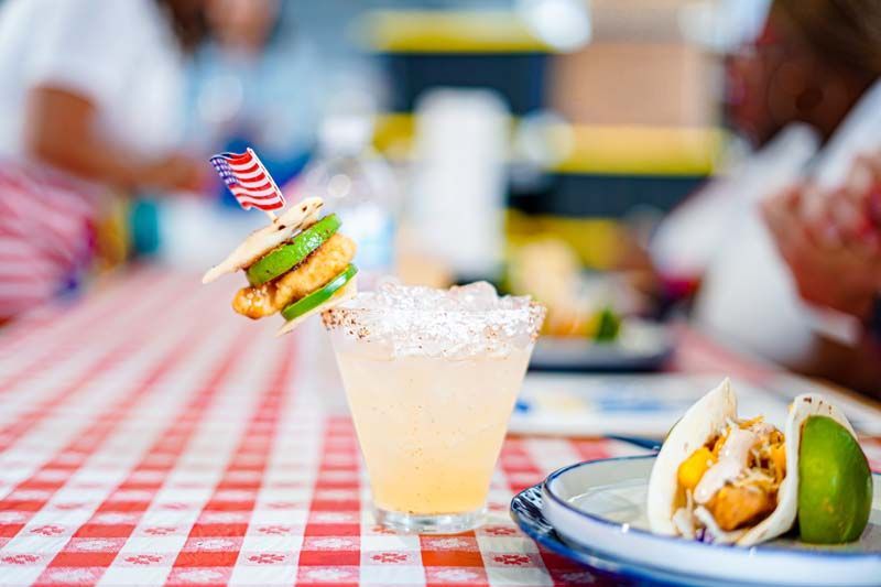 A margarita is sitting on a table next to a plate of food.