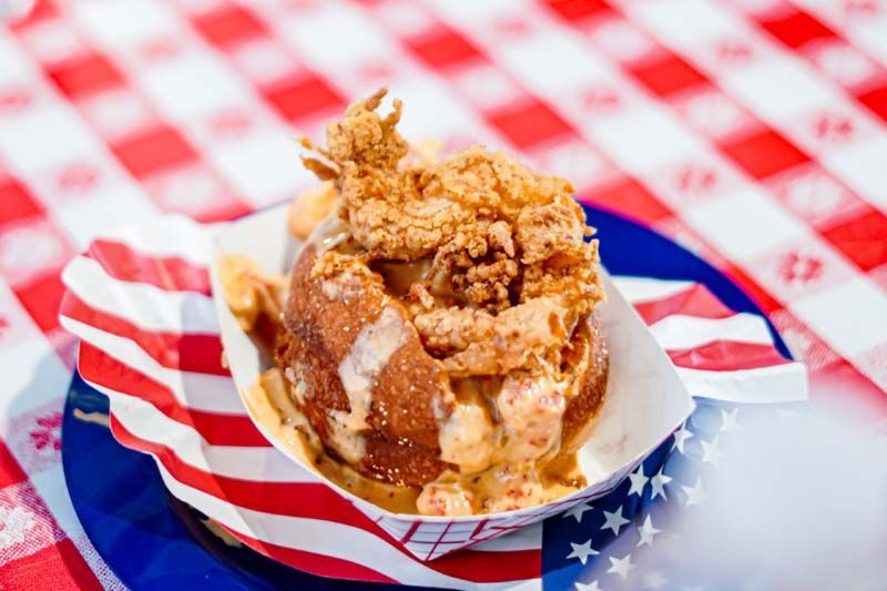 A close up of a donut on a paper plate on a table.