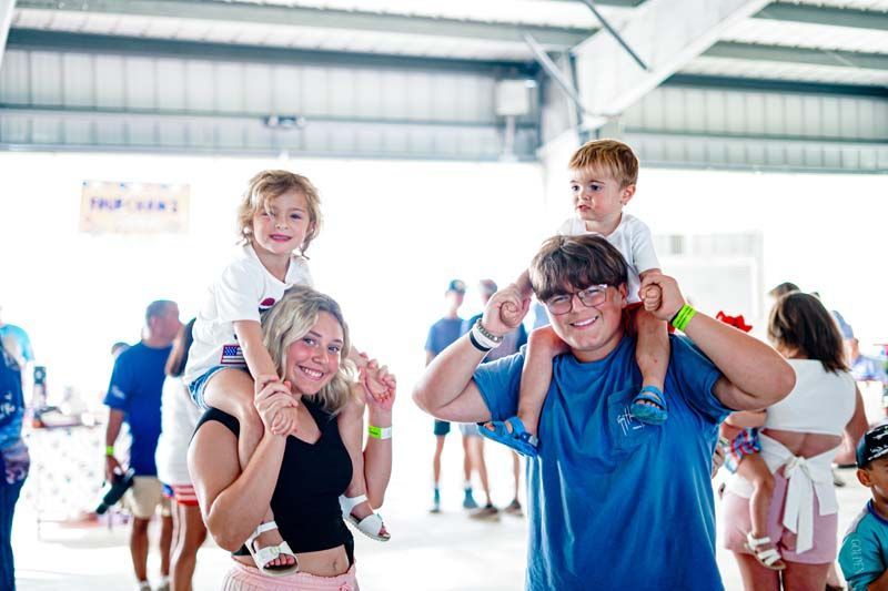 A woman is carrying two children on her shoulders.