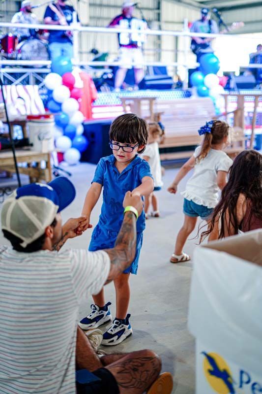 A man is holding the hand of a little boy at a party.