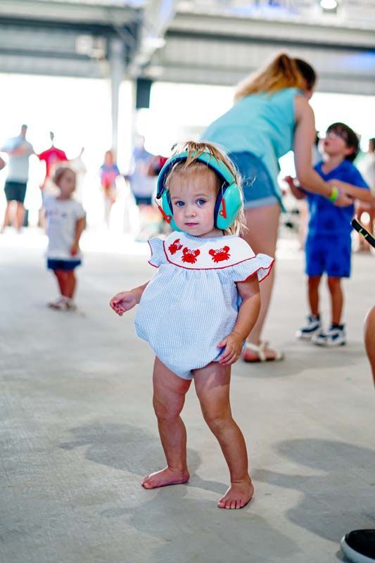A little girl wearing headphones is standing in a room.