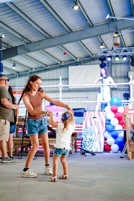 A woman and a little girl are dancing in a room.