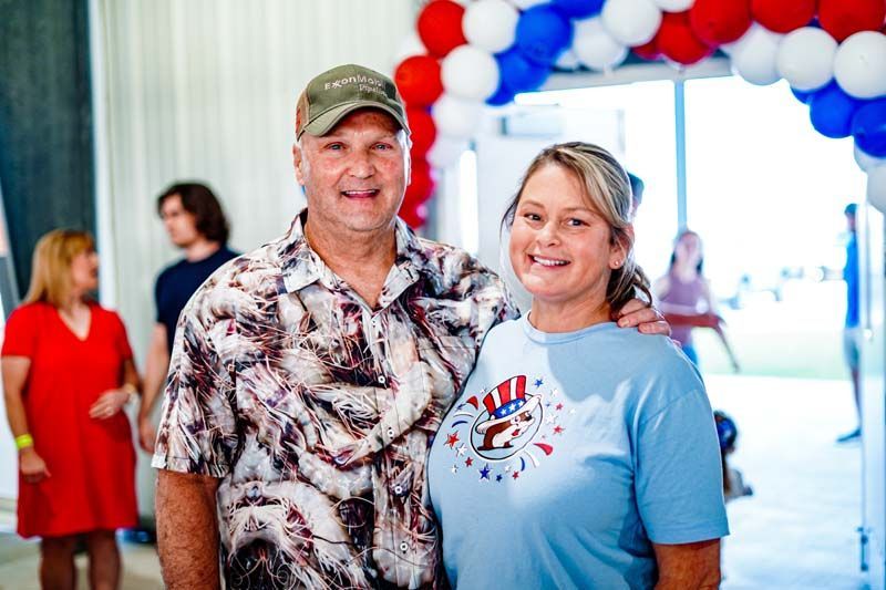 A man and a woman are posing for a picture in front of balloons.