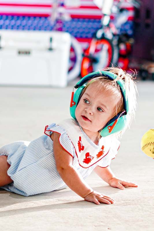 A little girl wearing headphones is crawling on the floor.
