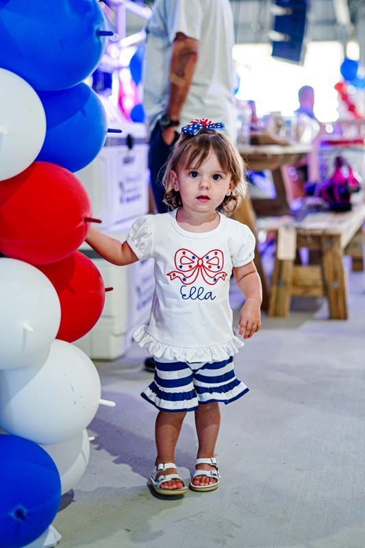 A little girl is standing in front of a bunch of balloons.