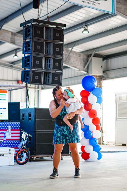 A woman is holding a baby in her arms and singing into a microphone.