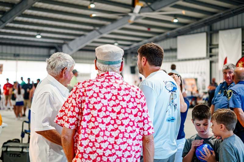 A group of men are standing in a room talking to each other.