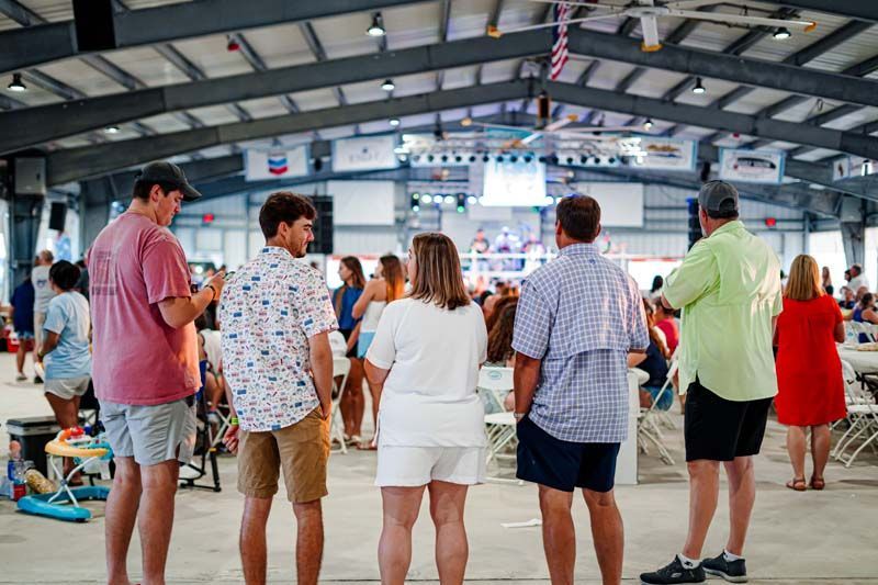A group of people are standing in a large room looking at something.