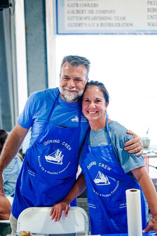 A man and a woman wearing blue aprons are posing for a picture.