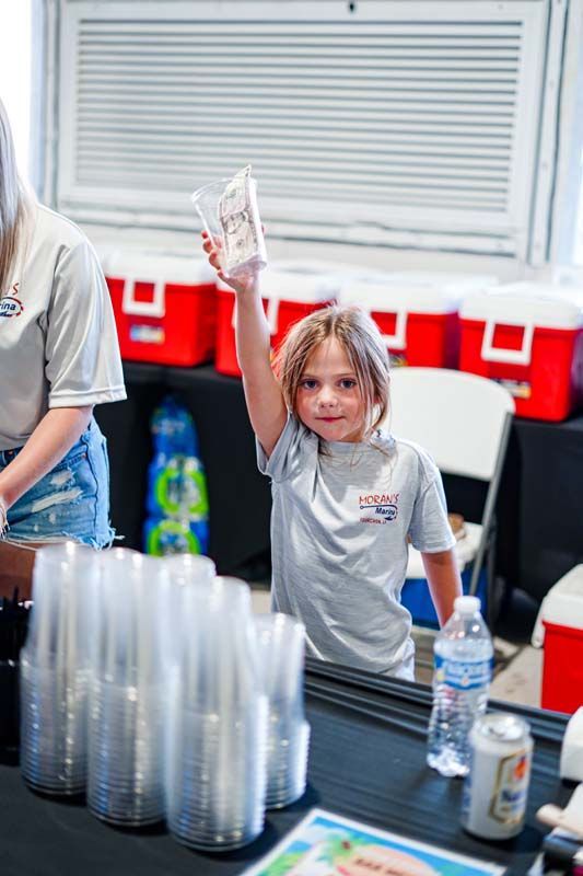 A little girl is standing in front of a counter holding a cup in her hand.