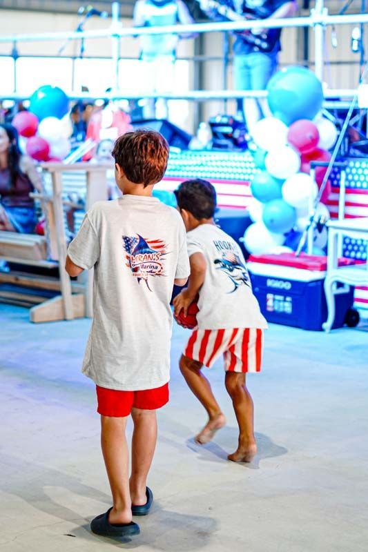 Two young boys are standing next to each other in a room with balloons.