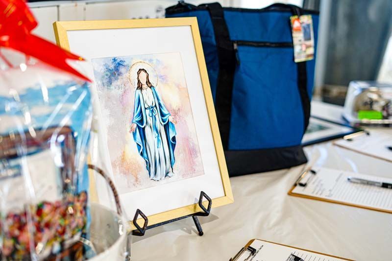 A painting of mary is sitting on a table next to a blue bag.
