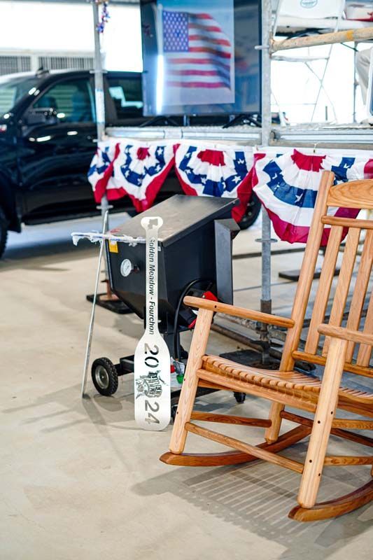 A wooden rocking chair is sitting in front of an american flag.