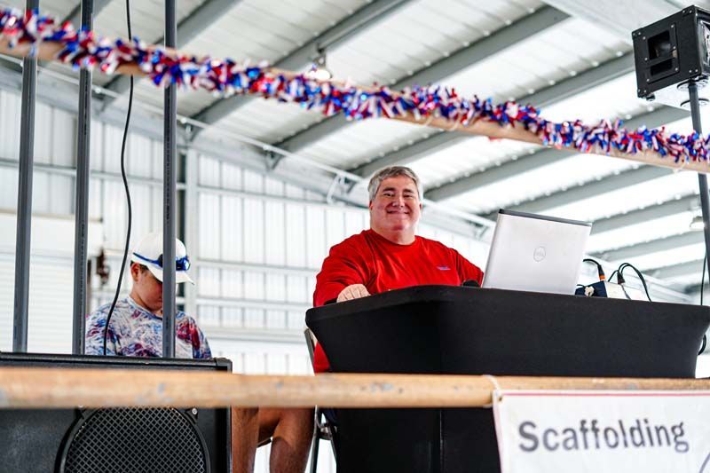 A man is sitting at a table in front of a sign that says scaffolding.