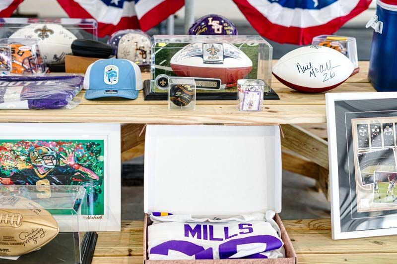 A table filled with lots of footballs and memorabilia including a mills jersey.