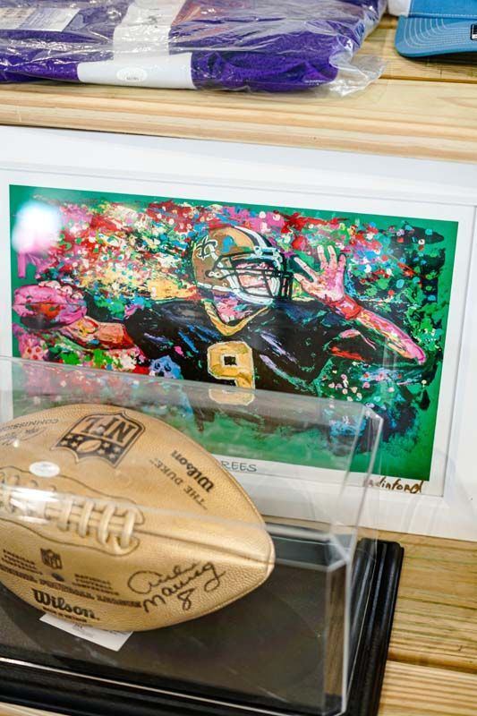 A football is in a display case next to a painting of a football player.
