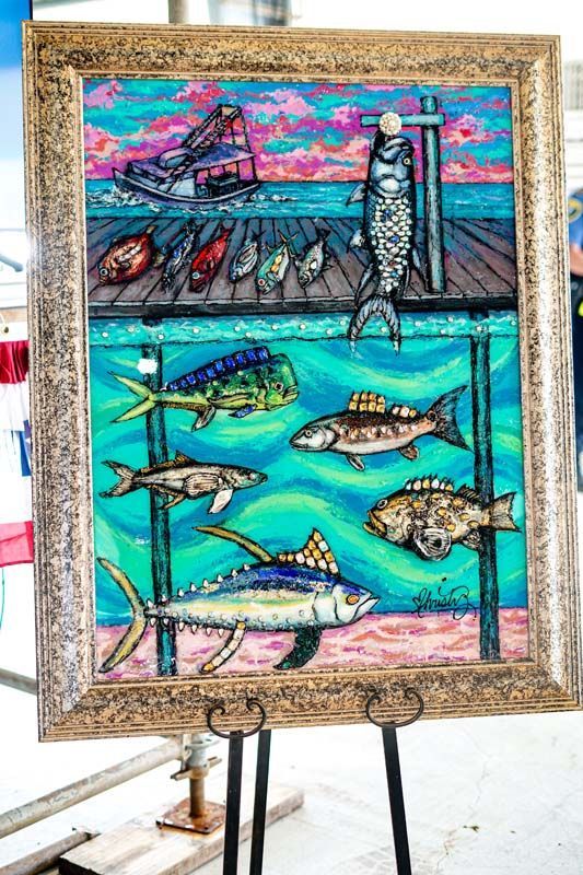 A painting of fish on a dock in a frame on a stand.