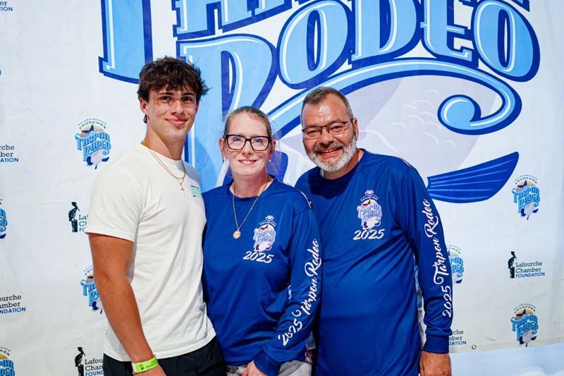 A man and two women are posing for a picture in front of a rodeo sign.