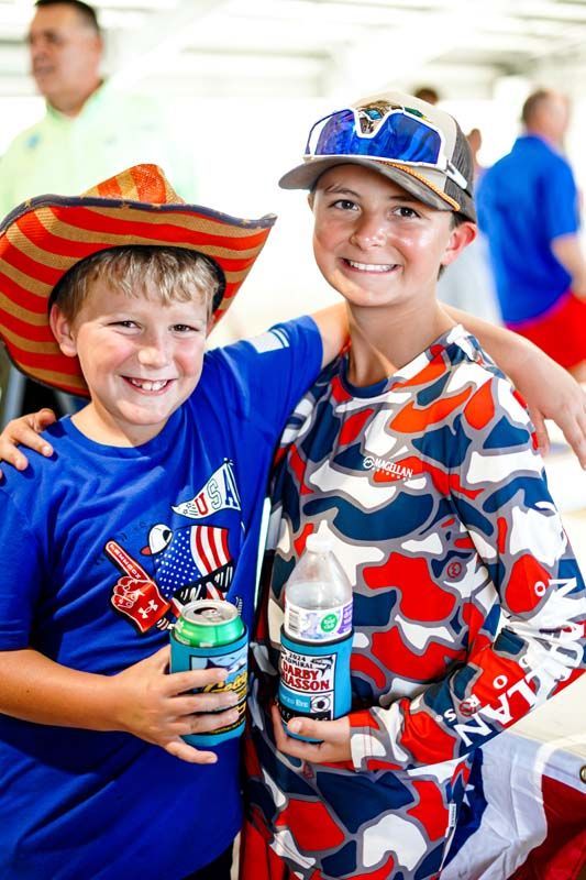 Two young boys are posing for a picture while holding cans of soda.