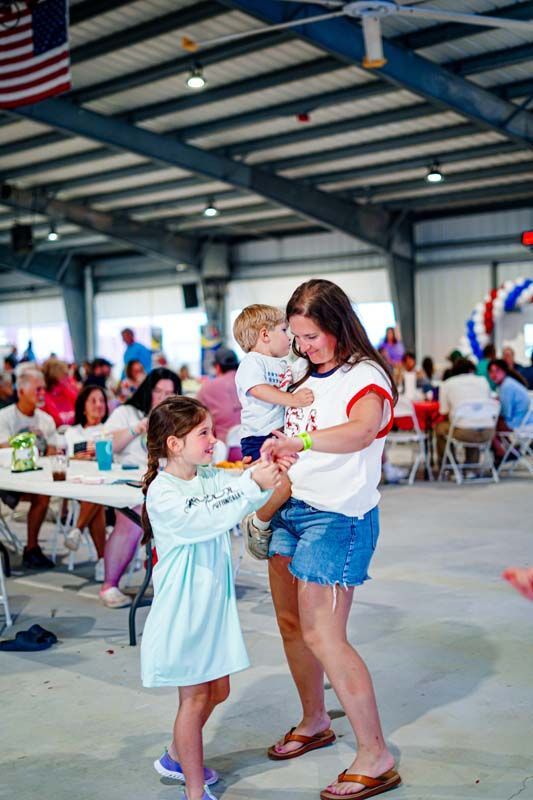 A woman and a little girl are dancing in a large room.