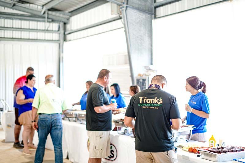 A group of people are standing around a table eating food.