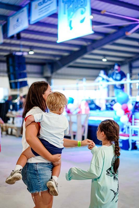 A woman is holding a child in her arms while two children are standing next to her.