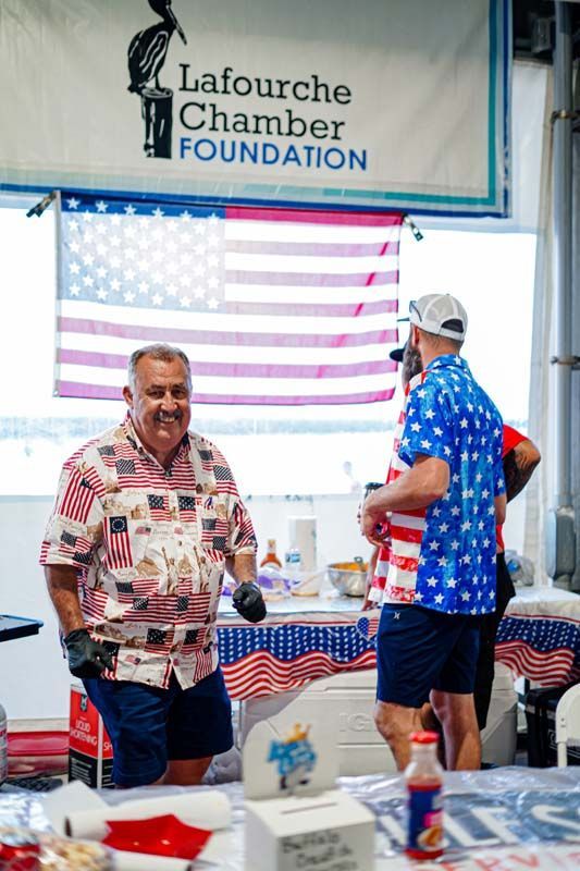 Two men are standing in front of a lafourche chamber foundation sign.