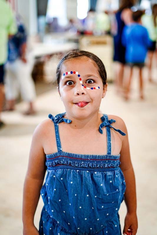 A little girl with red , white and blue paint on her face.